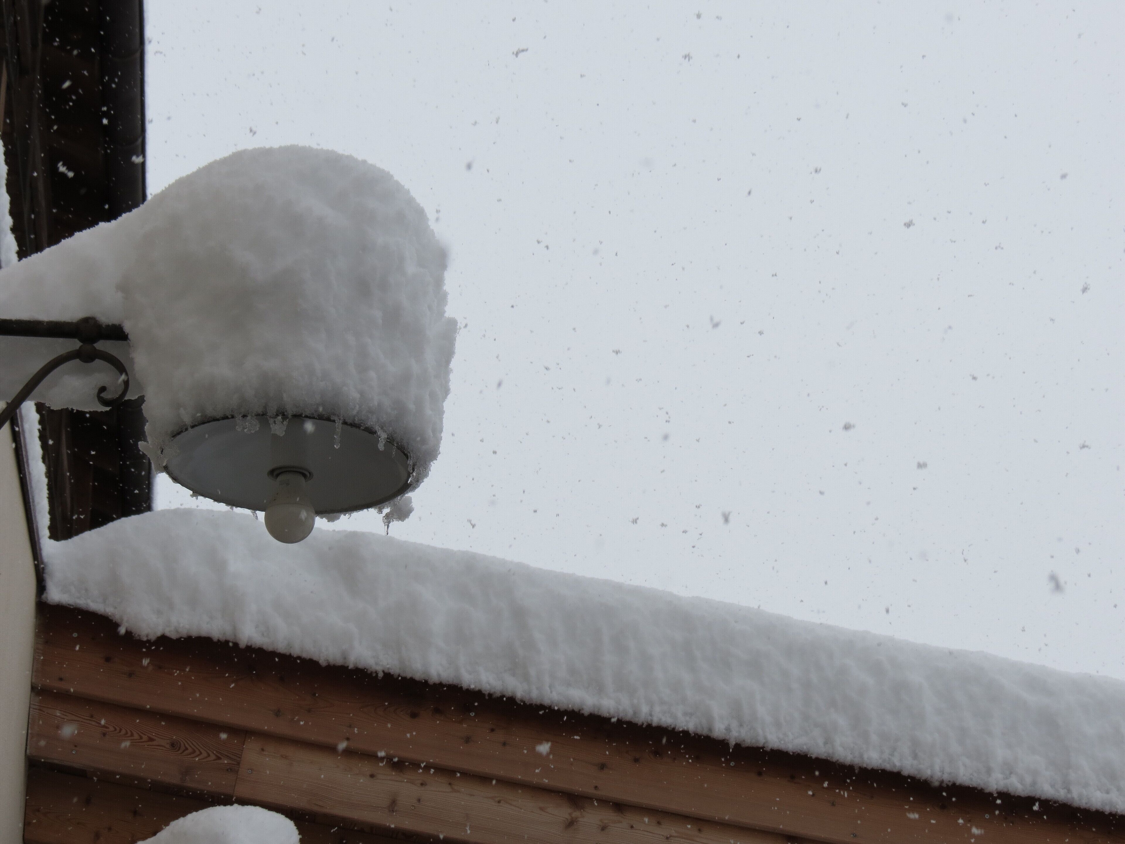 Ein mit Schnee bedeckter Fensterbrett mit einer schneelastigen Straßenlaterne.