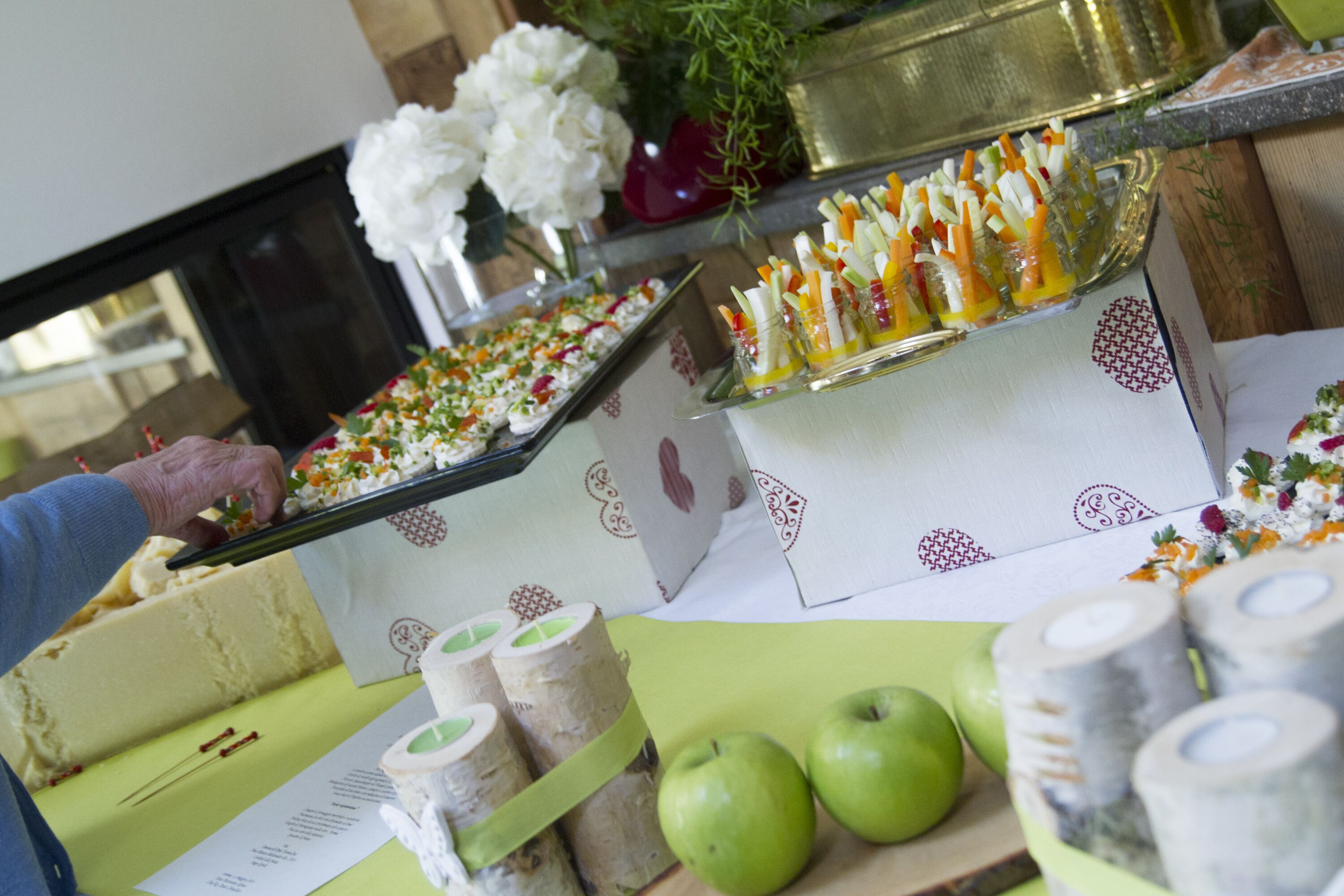 A buffet table with various food items, including a cake, green apples, and a tray of appetizers.
