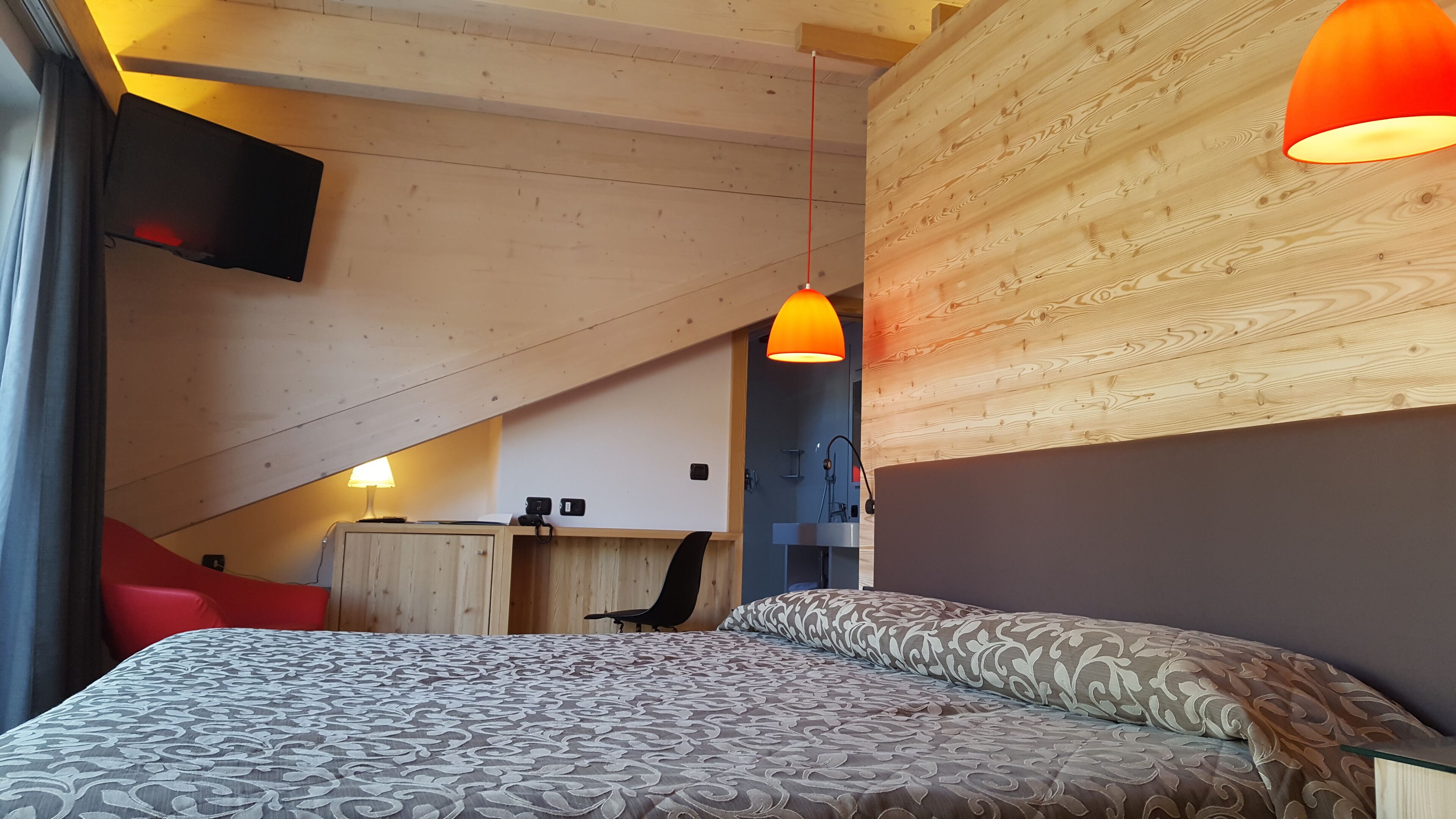 A bedroom with a bed, a desk, and a chair.