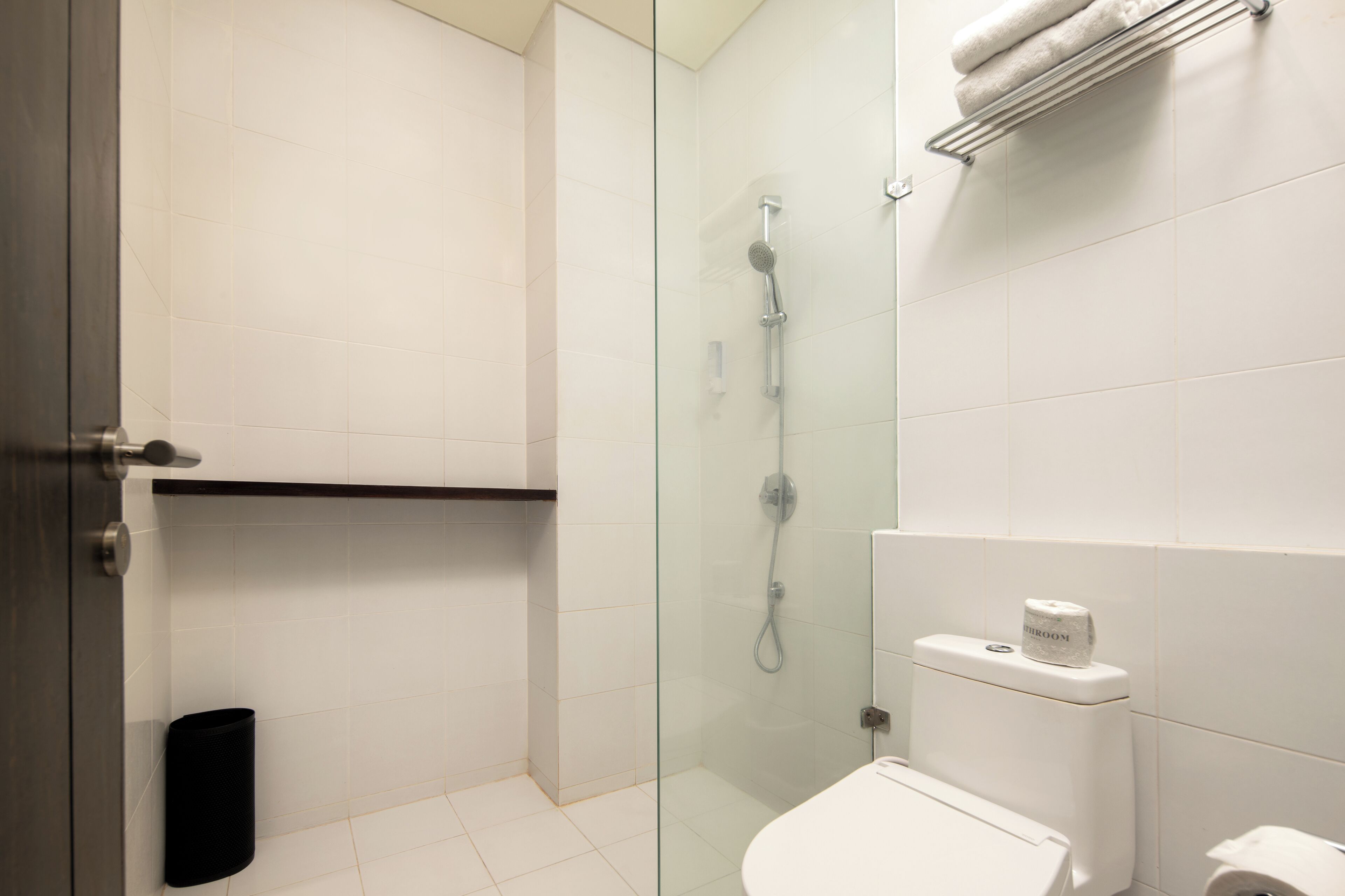 A modern bathroom with a glass-enclosed shower, a white toilet, and a towel rack.