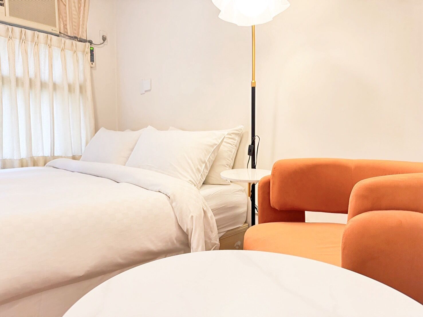 A hotel room with a bed, a small round table, and an orange chair.