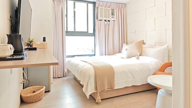 A modern bedroom with a bed, bedside table, and a desk with a computer.