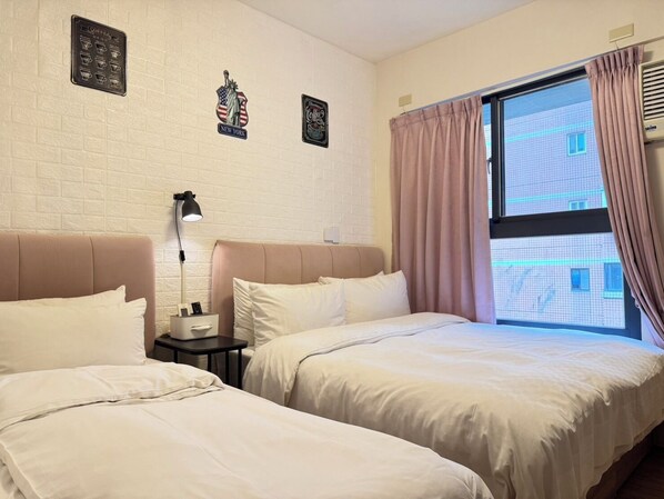 A hotel room with two beds, a nightstand with a lamp, and a window with curtains.