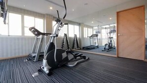 A gym with stationary bikes, treadmills, and a mirrored wall. - Tokyo International Hotel (Taipei)