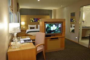 A hotel room with a bed, a desk with a lamp, a television, and a mirror. - Tokyo International Hotel (Taipei)
