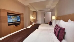 A hotel room with a large bed, a TV mounted on the wall, and a bedside table with a lamp. - Tokyo International Hotel (Taipei)