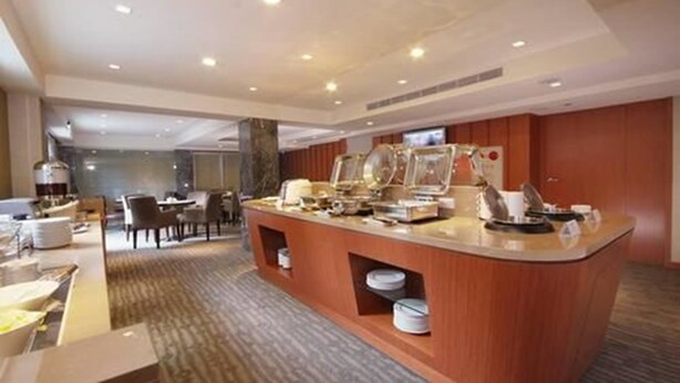 A buffet area with a marble countertop, multiple serving stations, and a seating area with chairs and tables. - Tokyo International Hotel (Taipei)
