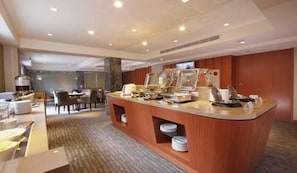 A buffet area with a marble countertop, multiple serving stations, and a seating area with chairs and tables. - Tokyo International Hotel (Taipei)