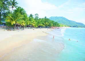 A beach with palm trees, a sandy shore, and a mountain in the background. - Lamai Inn 99 Bungalows (Koh Samui)
