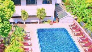 A rectangular swimming pool with lounge chairs and a building with a tiled roof in the background. - Lamai Inn 99 Bungalows (Koh Samui)