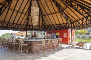 Eine Außenbar mit Korbstühlen, einer Bar und einer hängenden Leuchte.