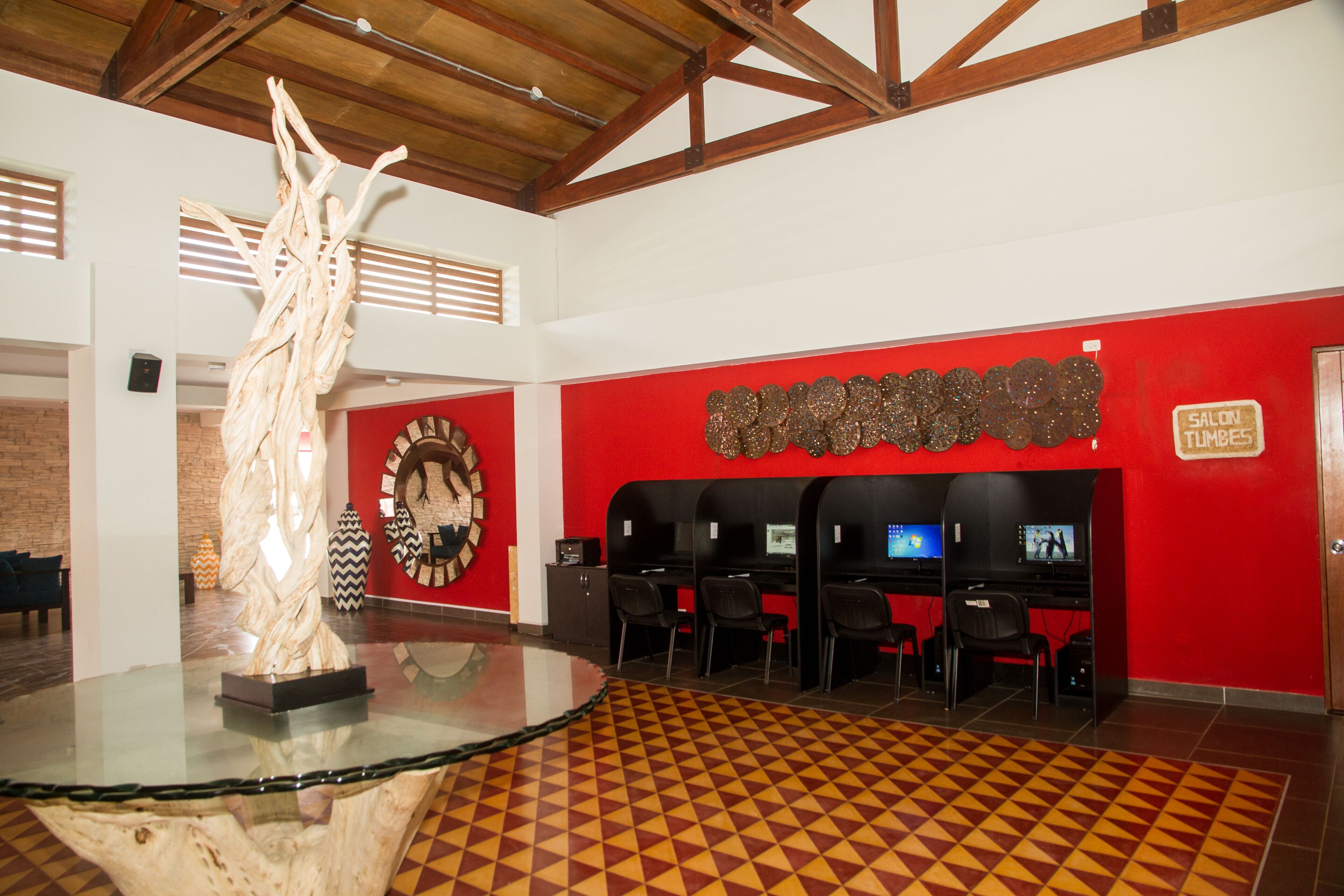 Un vestíbulo con una mesa de vidrio, paredes rojas, un reloj y un letrero que dice "SALON TUMBES".