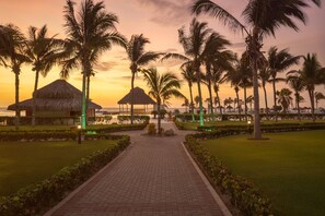 A pathway leading to a beach area with palm trees and thatched-roof structures. - Royal Decameron Punta Sal (Canoas de Punta Sal)