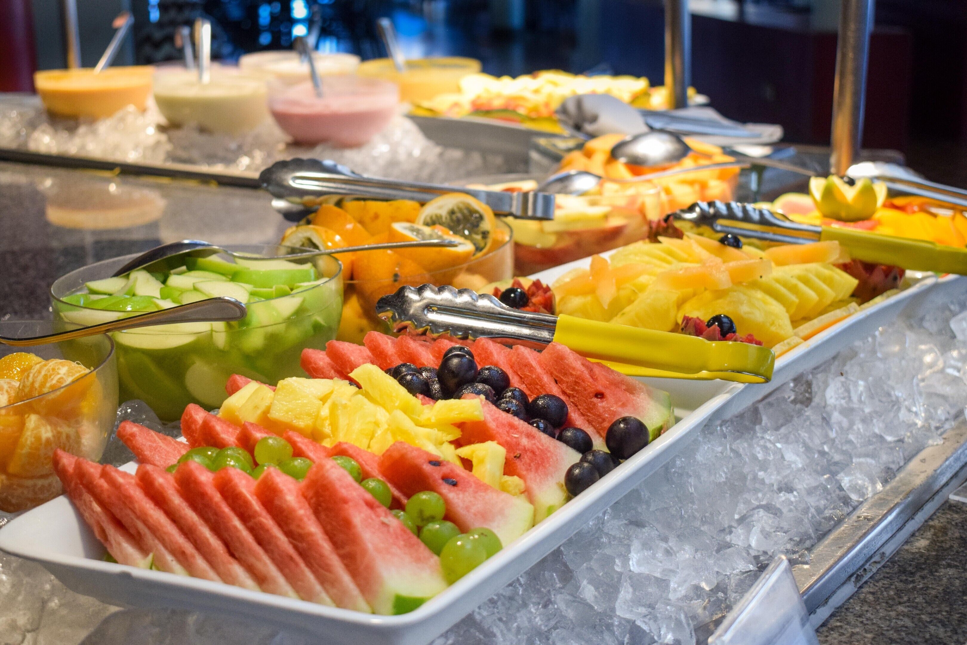 Un bufé con diversas frutas y una selección de bebidas.