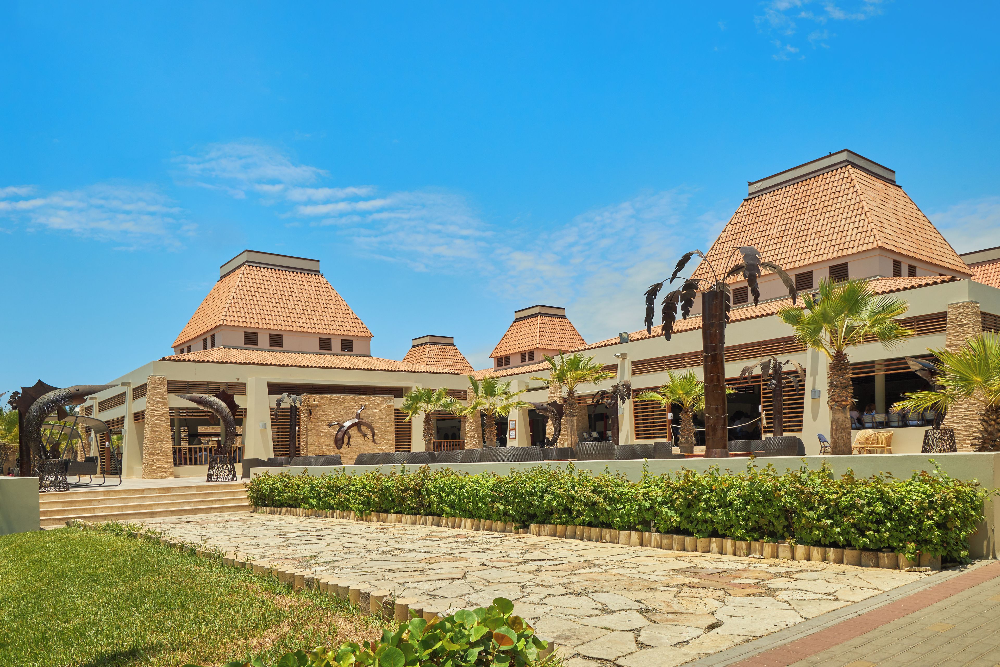 A hotel with multiple buildings, each featuring a terracotta-tiled roof and a central courtyard with seating areas.