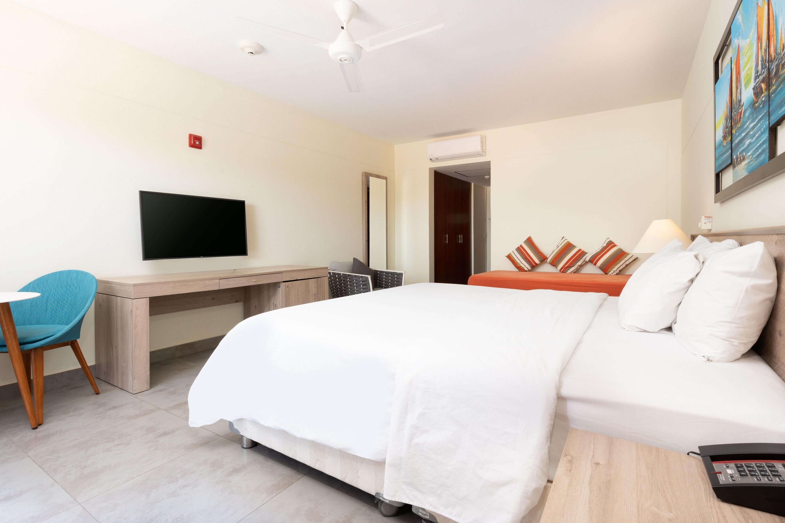 Une chambre d’hôtel avec un lit, un bureau, une chaise, une télévision et un tableau au mur.