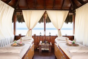 A room with two beds, a wooden floor, a view of the beach, and a thatched roof. - Royal Decameron Punta Sal (Canoas de Punta Sal)