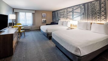 Una habitación de hotel con dos camas, un escritorio, un televisor y una ventana con cortinas.
