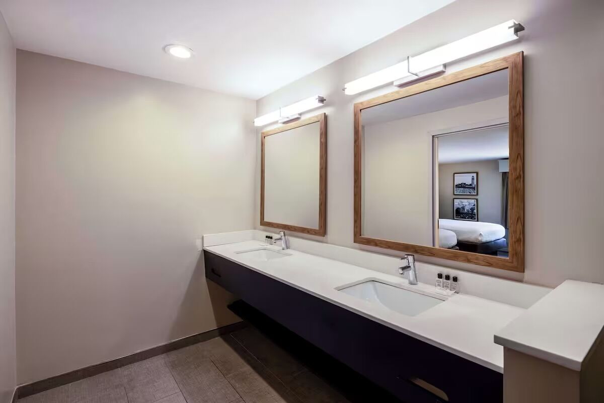 A modern bathroom with two sinks, mirrors, and overhead lighting.