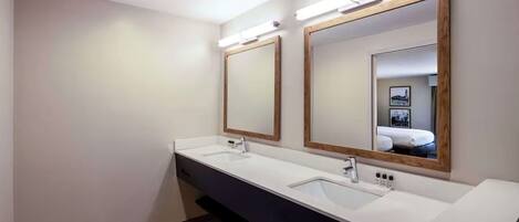 A modern bathroom with two sinks, mirrors, and overhead lighting.