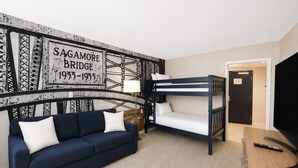 A room with a bunk bed, a sofa, a lamp, and a wall with a historical bridge sign. - Cape Cod Family Resort and Parks (West Yarmouth)