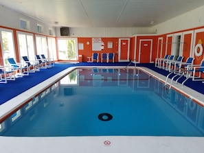 An indoor swimming pool with blue water, surrounded by orange walls and white doors. - Cape Cod Family Resort and Parks (West Yarmouth)