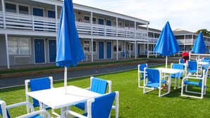 A motel with outdoor seating and blue umbrellas. - Cape Cod Family Resort and Parks (West Yarmouth)