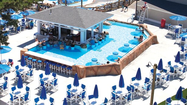 A pool area with a bar and lounge chairs. - Cape Cod Family Resort and Parks (West Yarmouth)