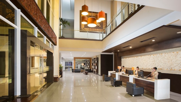 A modern hotel lobby with a reception desk, seating area, and a staircase leading to an upper level. - Hotel Santika Bengkulu (Bengkulu)