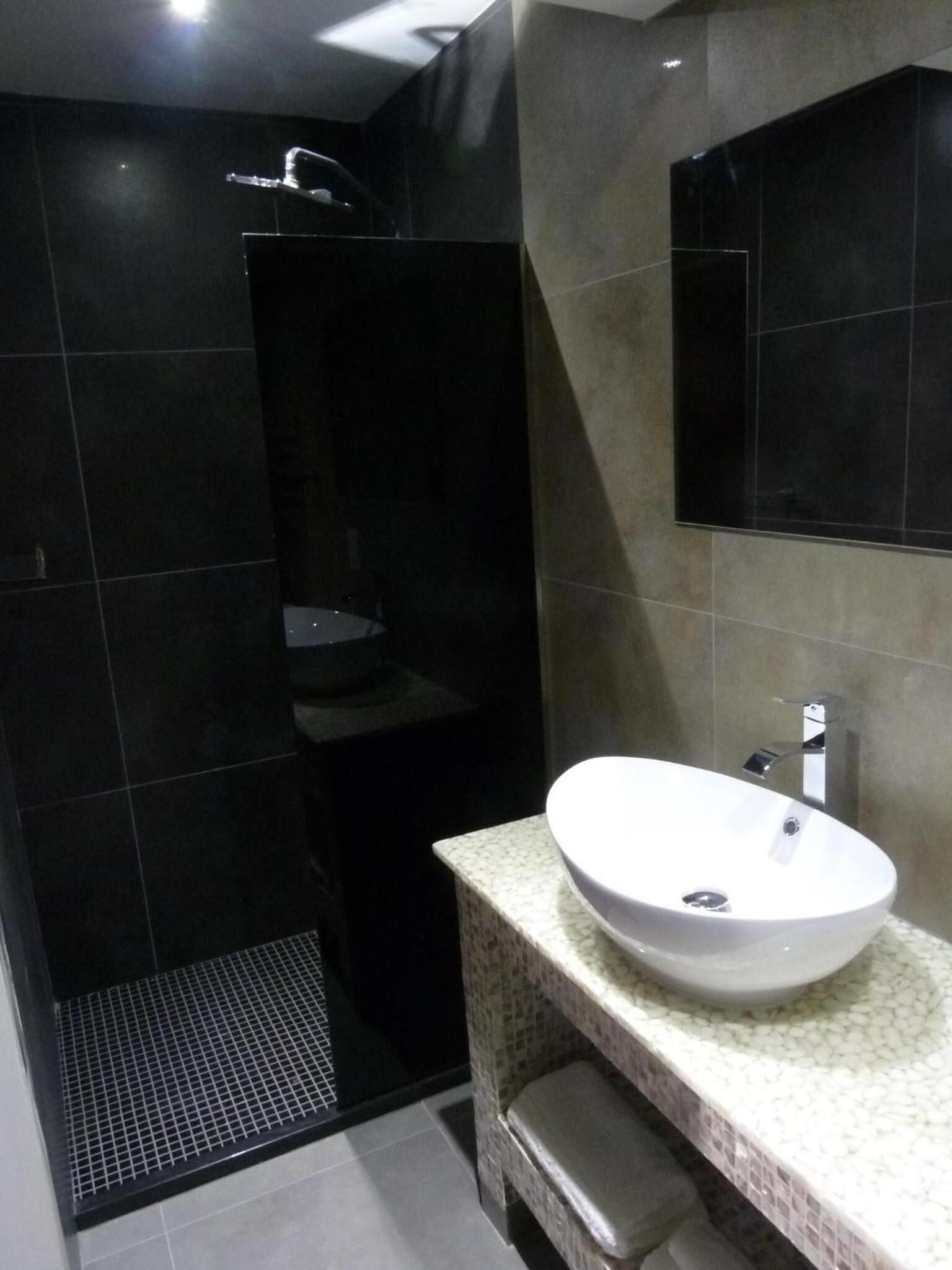 Un baño moderno con un lavabo blanco grande, un espejo y un box de ducha.