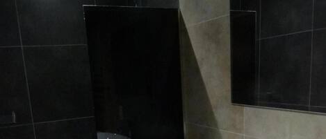 Un baño moderno con un lavabo blanco grande, un espejo y un box de ducha.