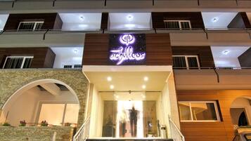 A hotel entrance with a modern design, featuring a prominent neon sign and a staircase leading to the entrance.