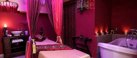 Une chambre à coucher avec un lit, une coiffeuse avec un miroir et une baignoire.
