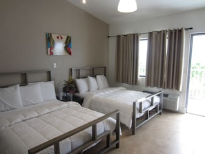 Habitación de hotel con dos camas individuales, una mesita de noche con una planta, un cuadro en la pared y una ventana con cortinas.