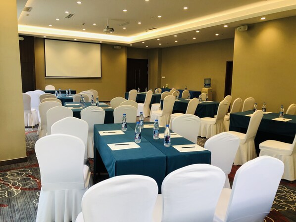 A conference room with rows of tables, white chairs, and water bottles.