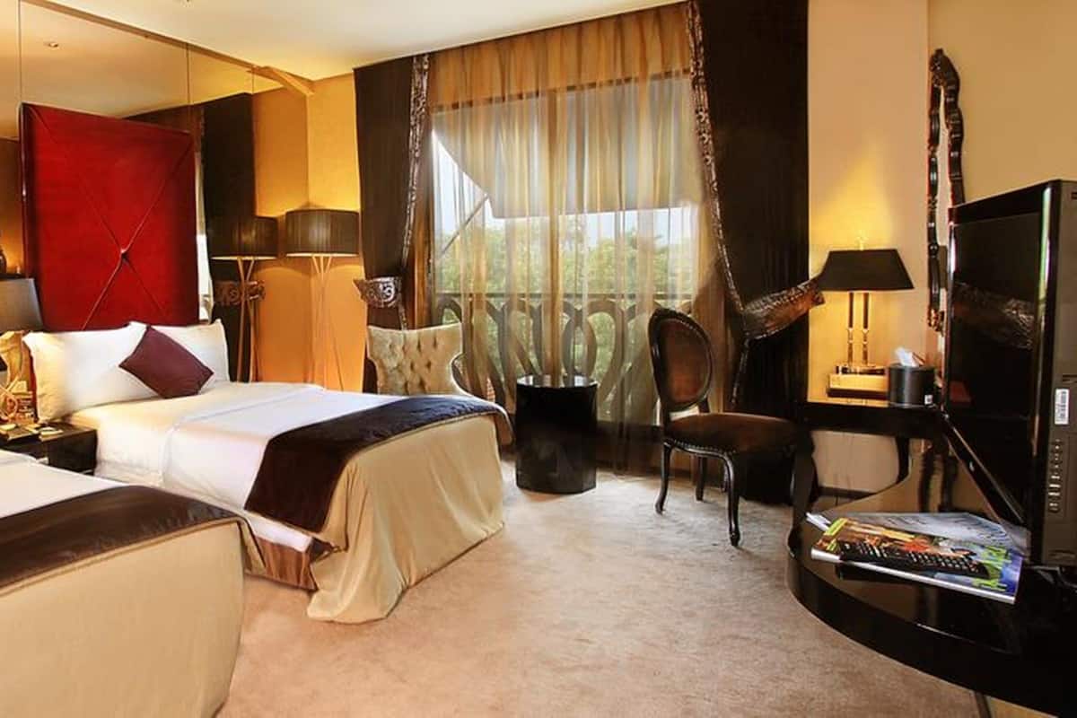 Une chambre d’hôtel avec deux lits, une télévision, un bureau et une chaise.