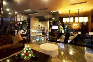 A modern lobby with a reception desk, seating area, and a decorative light fixture. - Amaroossa Hotel Bandung Indonesia (Bandung)
