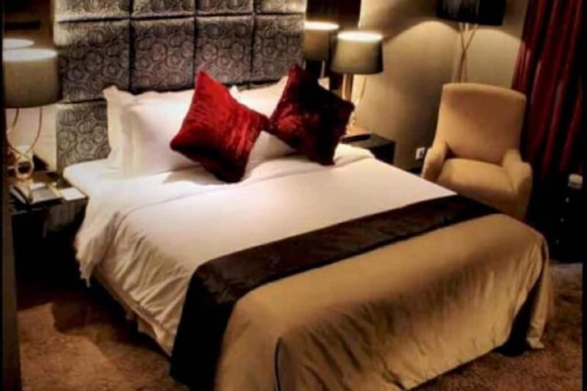 Une chambre d’hôtel avec un lit, une chaise, une table de chevet et une lampe.