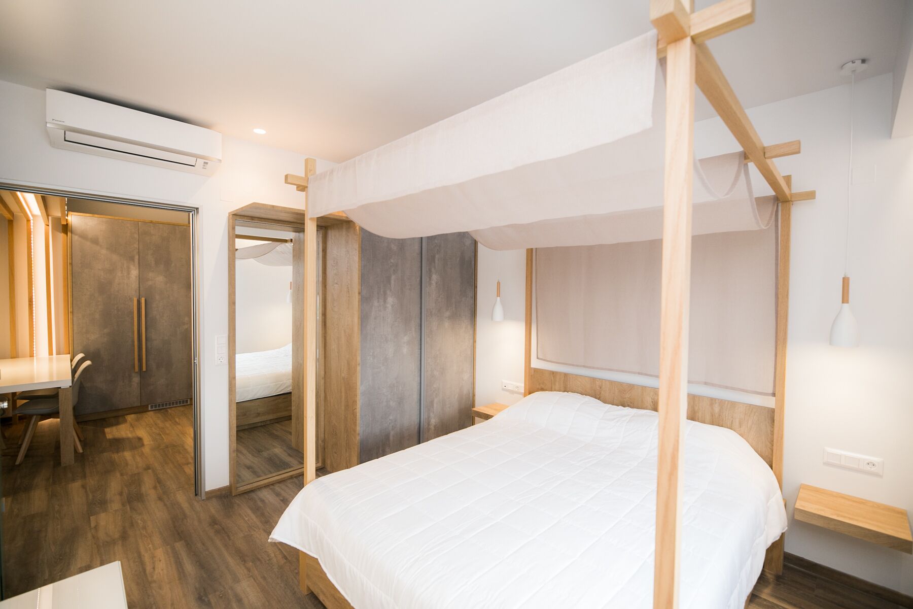 Ein modernes Schlafzimmer mit einem hölzernen Himmelbett, einem Schreibtisch aus Holz und einem Kleiderschrank.