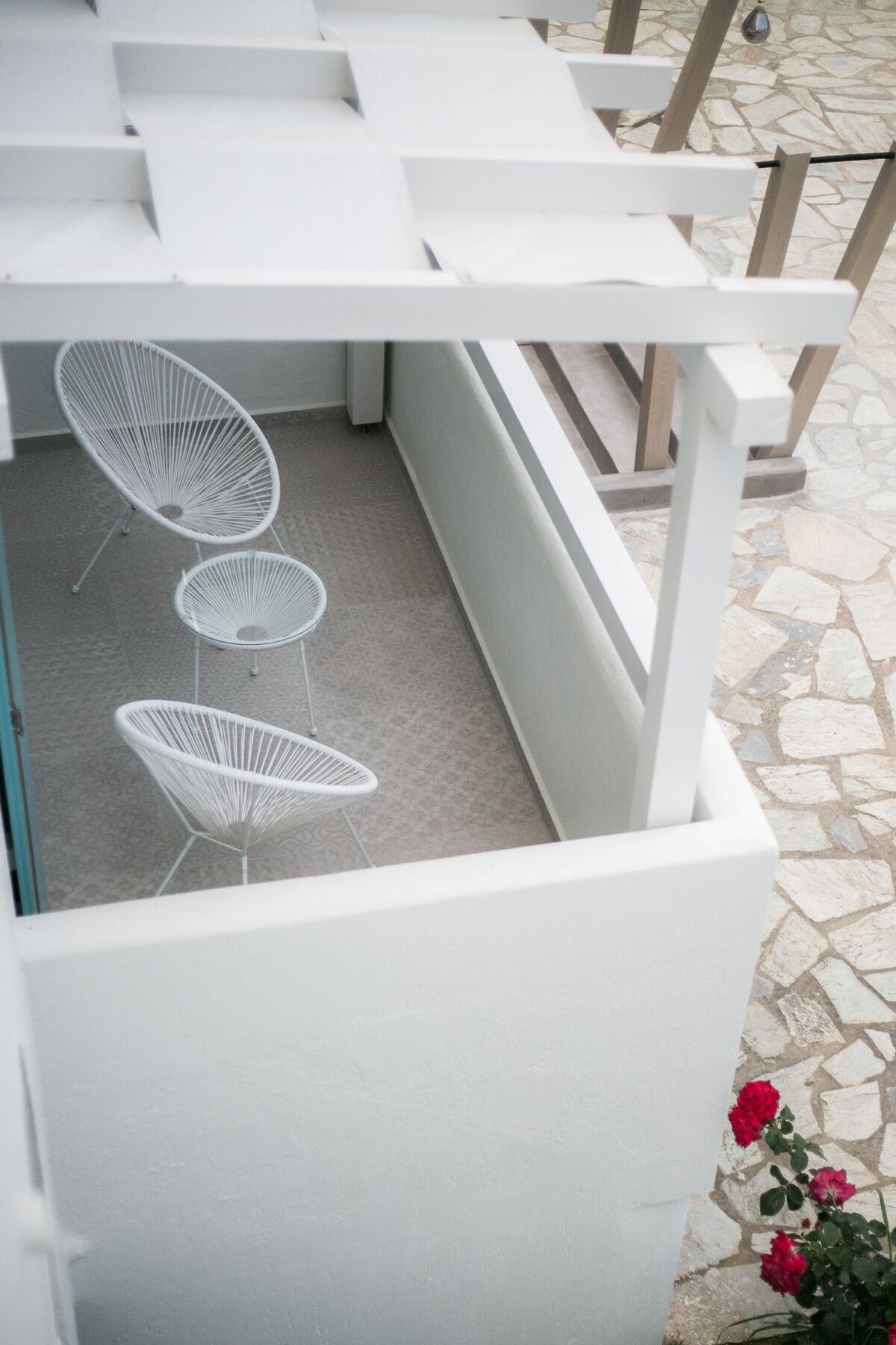 A covered outdoor seating area with white metal chairs and a white table.