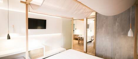 Een moderne slaapkamer met een bed, bureau en televisie.