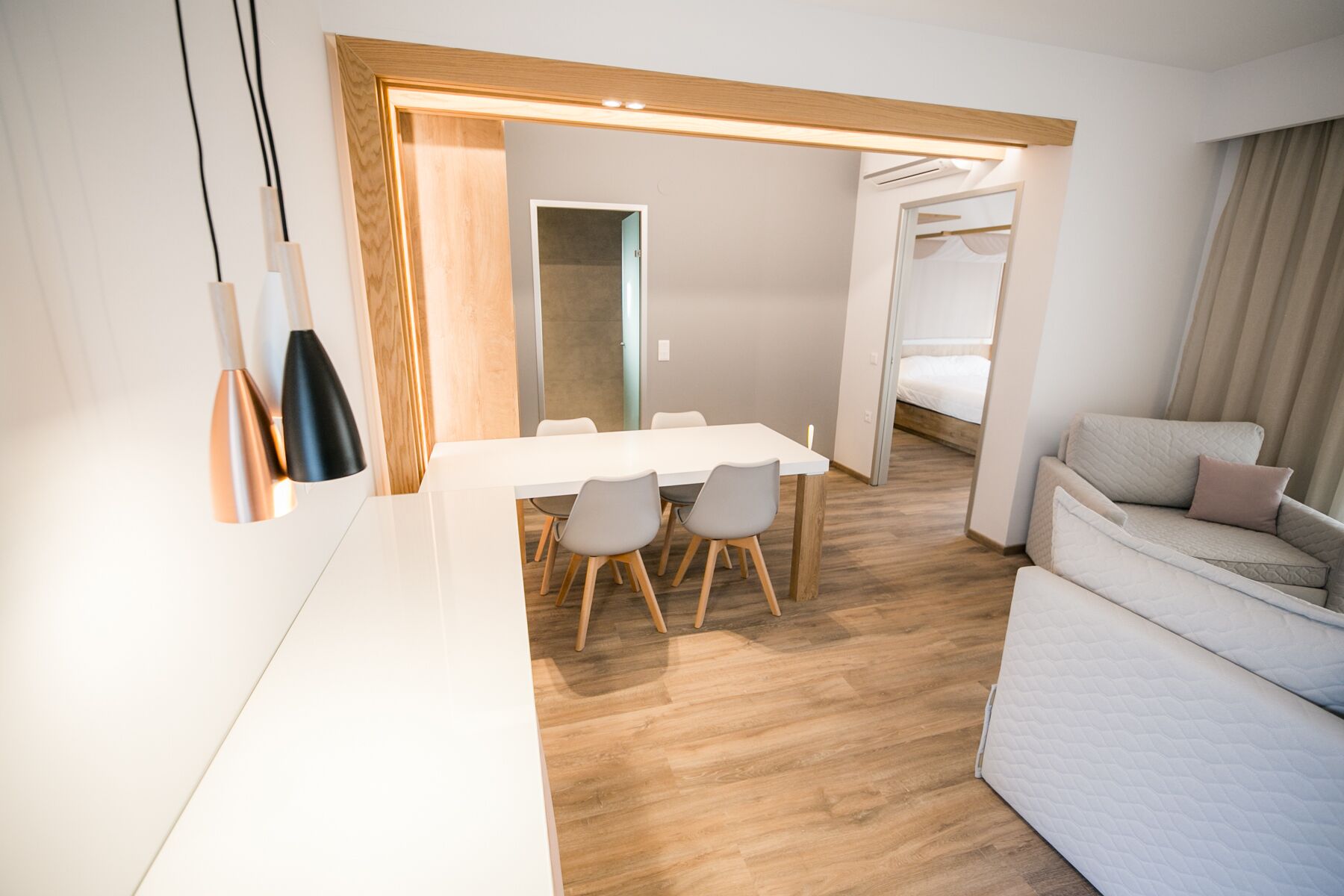 A modern hotel room with a dining area, a sofa, and a bed.