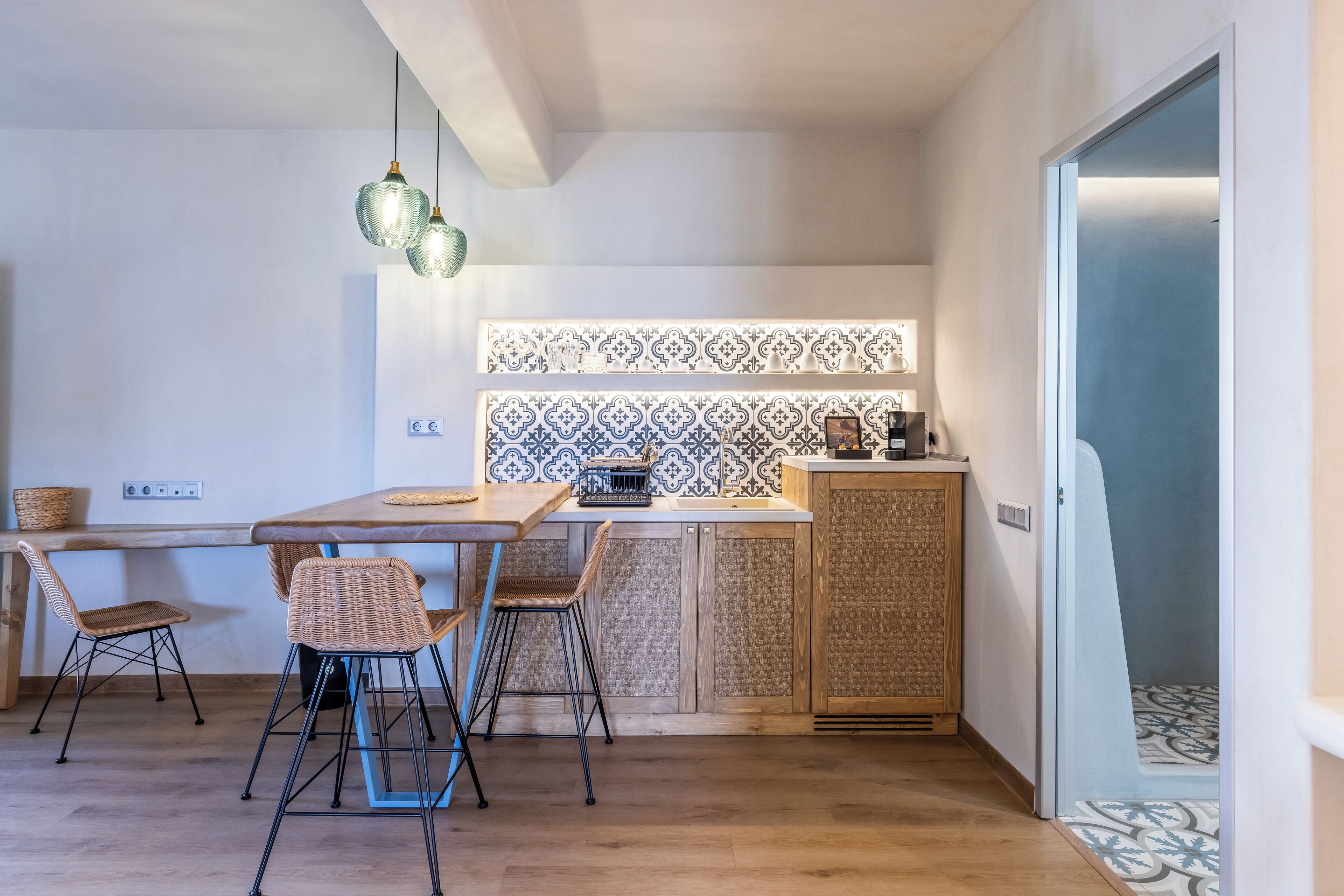 Une cuisine moderne avec une table en bois, des chaises en osier et un crédence décorée.