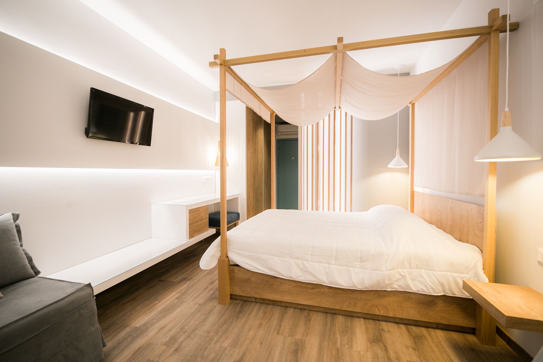 Ein modernes Schlafzimmer mit einem Himmelbett, einem Flachbildfernseher an der Wand und einem Nachttisch mit Lampe.