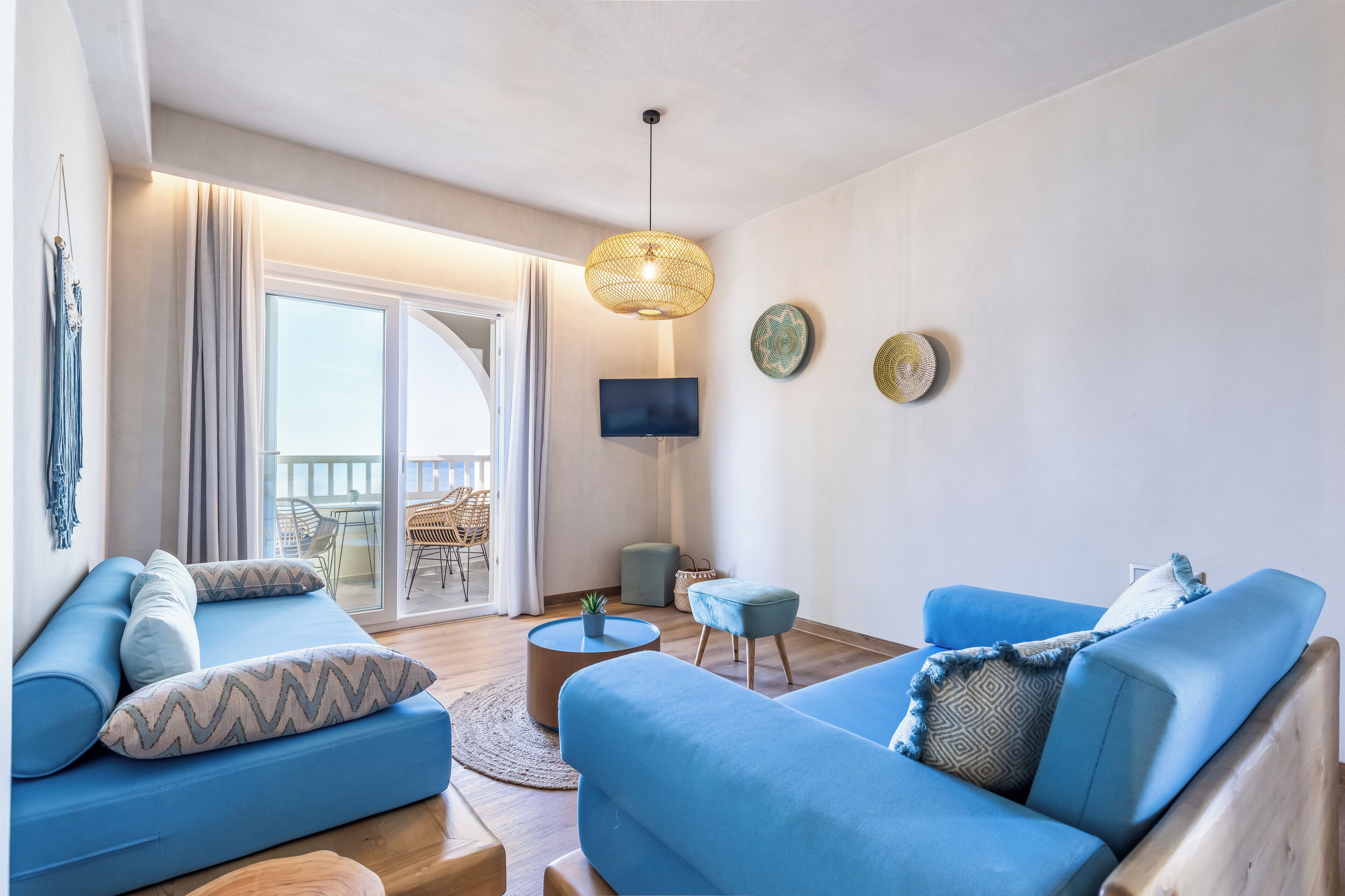 Una sala de estar moderna con un sofá azul, una mesa de centro redonda y un televisor en la pared.