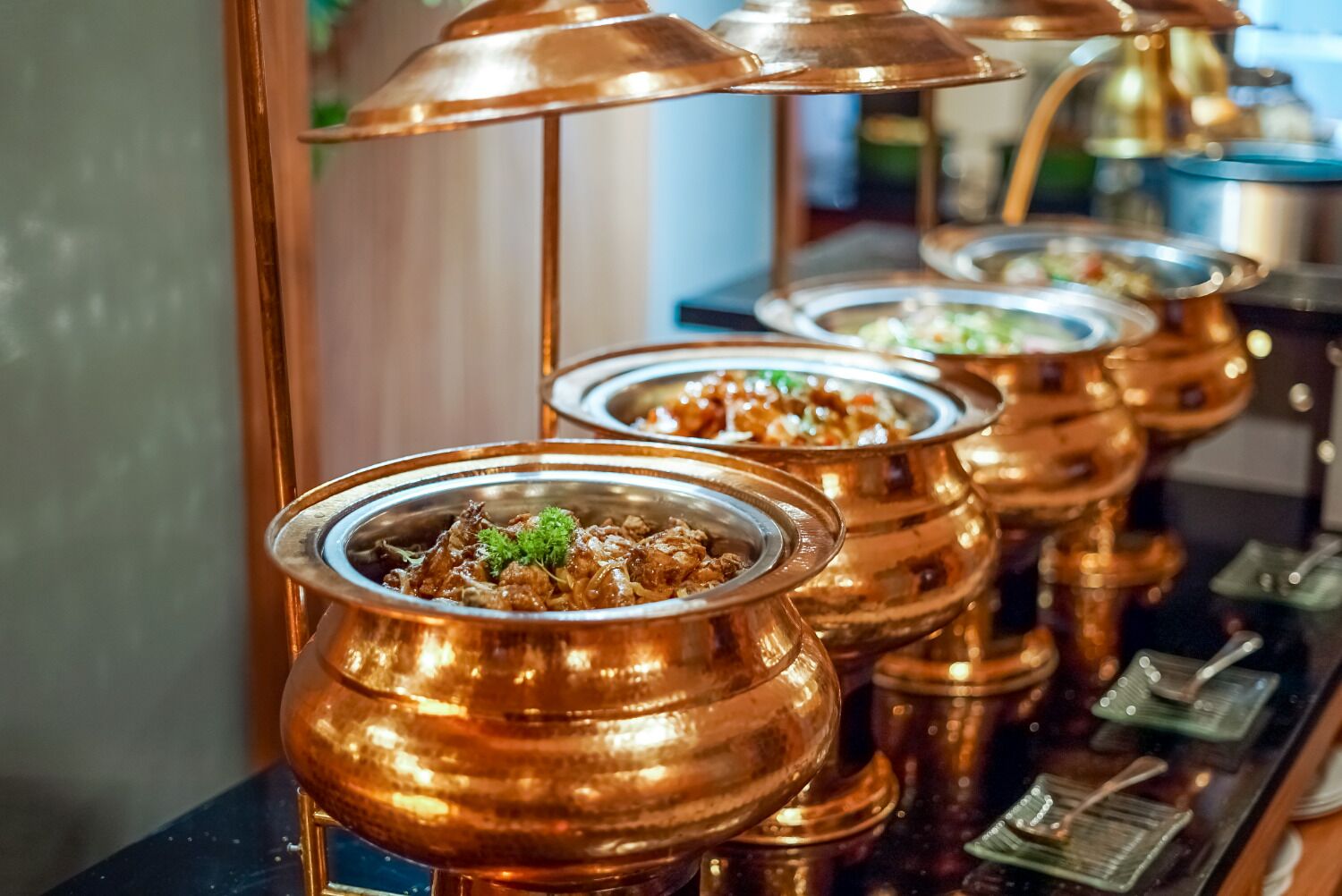 Un buffet avec de nombreux plats présentés dans des récipients en cuivre.