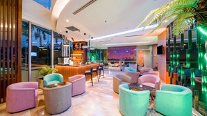 Un vestíbulo moderno con una zona de bar, asientos y un amplio ventanal con vistas a la ciudad.