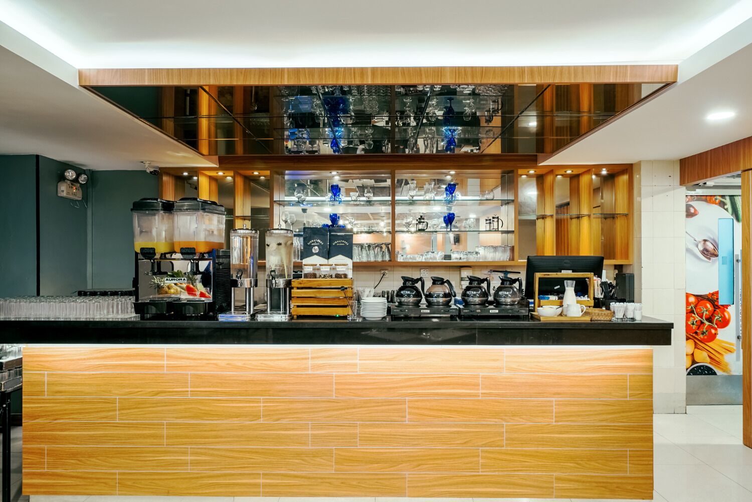 Una cocina moderna con encimera de madera, cafeteras y cristalería en estantes.