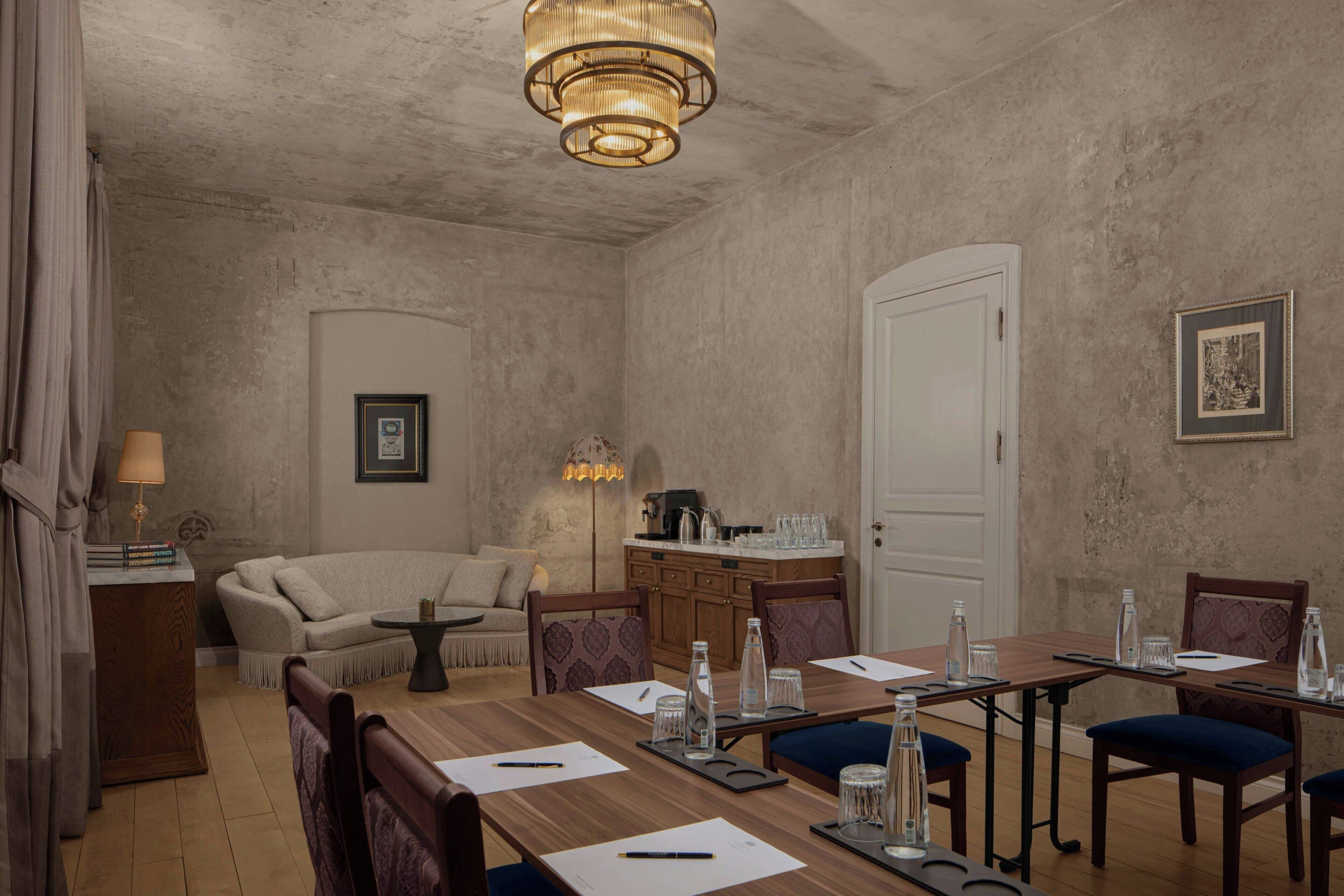 Una habitación con una mesa de comedor de madera, sillas, un sofá, una mesita auxiliar con una lámpara y un aplique de techo.