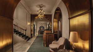 Un vaste hall avec un sol en marbre, un escalier, un coin bar et un espace détente avec une lampe.